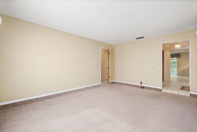 unfurnished room with light carpet, visible vents, and baseboards