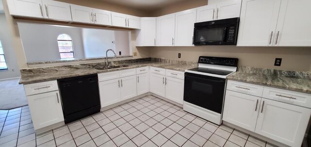 kitchen featuring black appliances, white cabinetry, dark stone countertops, and a sink