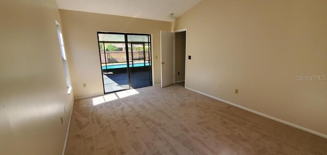 carpeted empty room with vaulted ceiling and baseboards