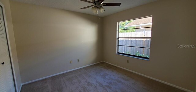spare room featuring ceiling fan, baseboards, and carpet flooring