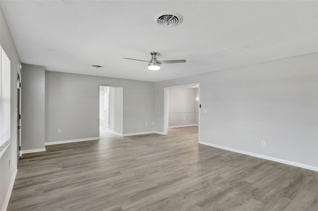 spare room featuring ceiling fan, baseboards, wood finished floors, and visible vents