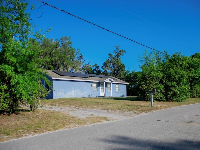 15 Estrella Rd, Debary, FL 32713 - view of front of home featuring solar panels, a front yard, and dirt driveway