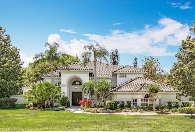 mediterranean / spanish home featuring a tiled roof, a front yard, and stucco siding