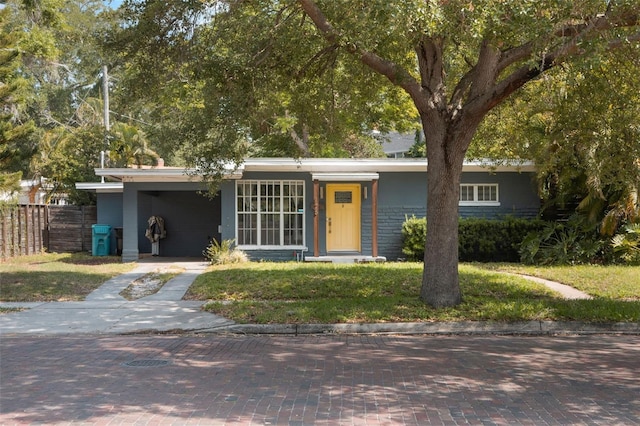view of front of property with fence, a carport, a front lawn, and concrete driveway