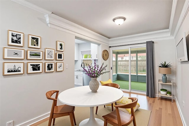 dining room featuring baseboards, ornamental molding, and light wood finished floors
