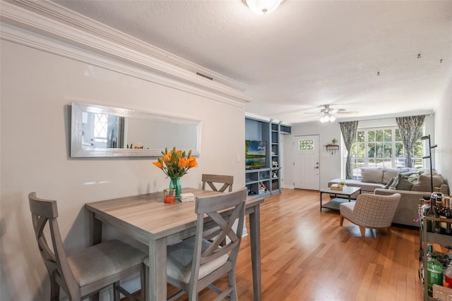dining space with ornamental molding, ceiling fan, visible vents, and light wood-style floors