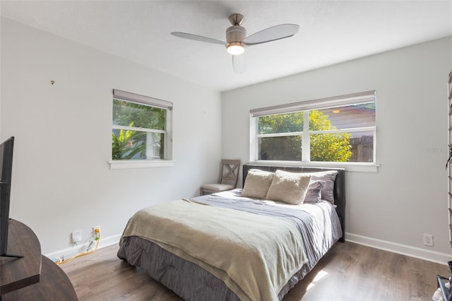 bedroom with baseboards, wood finished floors, and multiple windows
