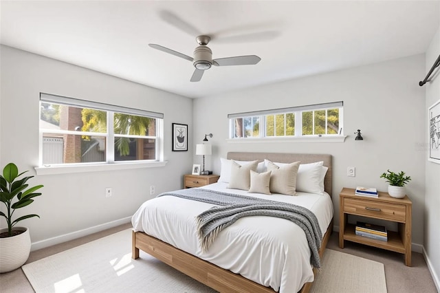 carpeted bedroom with ceiling fan, baseboards, and multiple windows