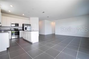 1163 James Paul Rd, Davenport, FL 33837 - kitchen with appliances with stainless steel finishes, a kitchen island, white cabinetry, dark tile patterned floors, and open floor plan