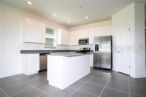 1163 James Paul Rd, Davenport, FL 33837 - kitchen featuring appliances with stainless steel finishes, white cabinetry, a kitchen island, recessed lighting, and dark countertops