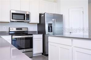 1163 James Paul Rd, Davenport, FL 33837 - kitchen with appliances with stainless steel finishes and white cabinets