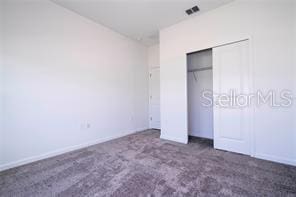 1163 James Paul Rd, Davenport, FL 33837 - unfurnished bedroom featuring dark carpet and a closet