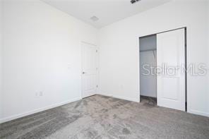 1163 James Paul Rd, Davenport, FL 33837 - unfurnished bedroom with carpet floors, baseboards, and a closet