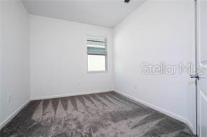 1163 James Paul Rd, Davenport, FL 33837 - unfurnished room with carpet, vaulted ceiling, and baseboards