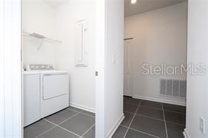 1163 James Paul Rd, Davenport, FL 33837 - laundry area featuring washer and clothes dryer, dark tile patterned floors, and baseboards