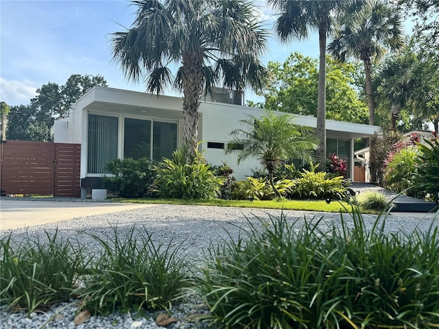 view of side of home with stucco siding and a gate