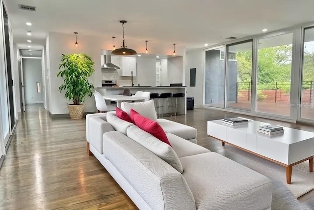 living room with baseboards, wood finished floors, visible vents, and recessed lighting