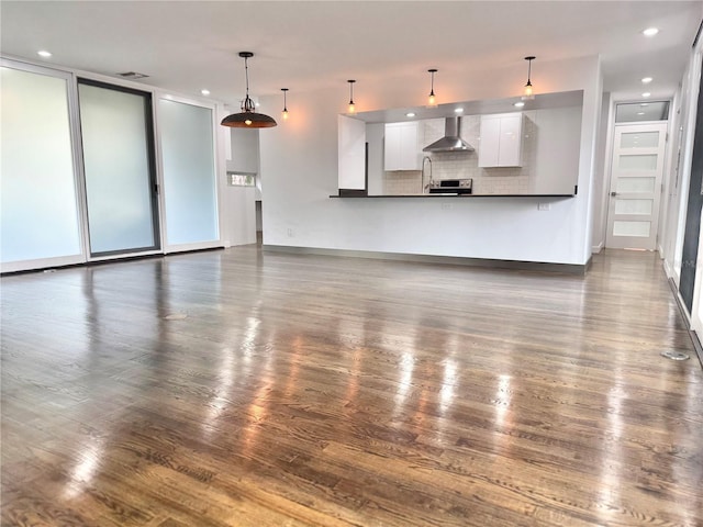 unfurnished living room with dark wood-style floors, a sink, baseboards, visible vents, and recessed lighting