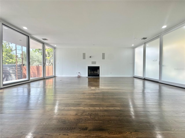 unfurnished living room featuring a wall of windows, visible vents, a fireplace, and dark wood finished floors