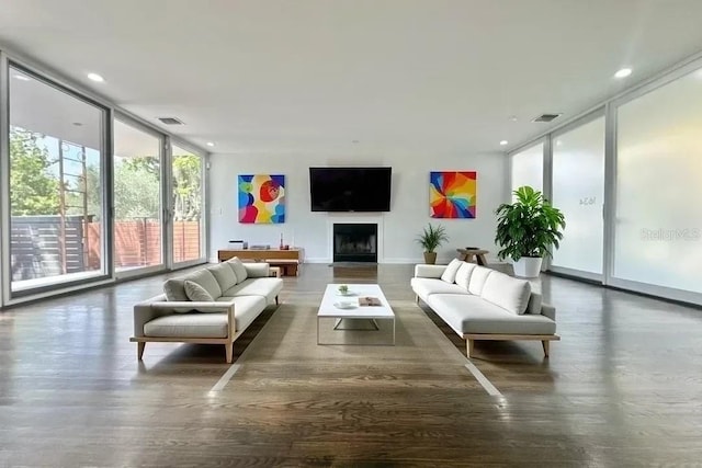 living room featuring a fireplace, wood finished floors, visible vents, and floor to ceiling windows