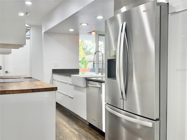 kitchen featuring wooden counters, stainless steel appliances, a sink, dark wood-type flooring, and white cabinetry