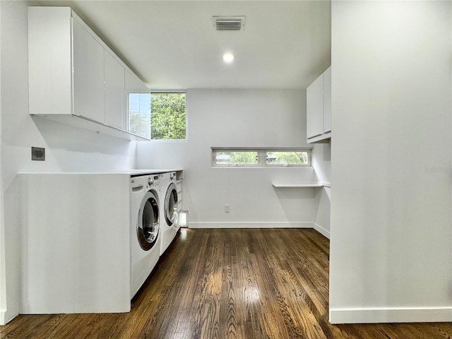 washroom with washing machine and clothes dryer, cabinet space, visible vents, baseboards, and dark wood-style floors