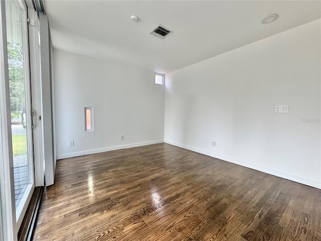 spare room with dark wood finished floors, visible vents, baseboards, and baseboard heating