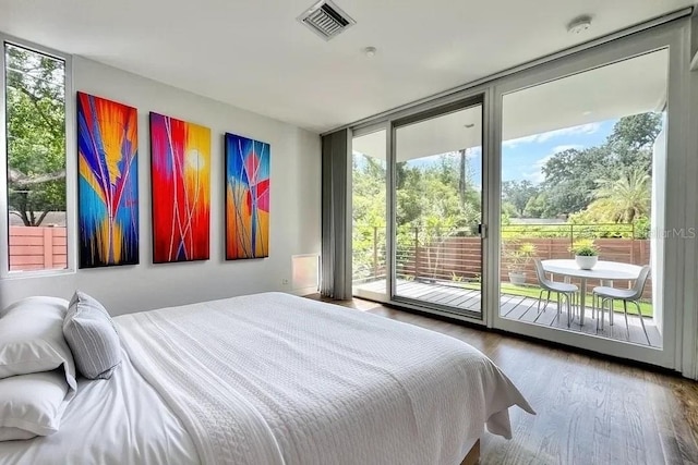 bedroom with expansive windows, wood finished floors, and multiple windows