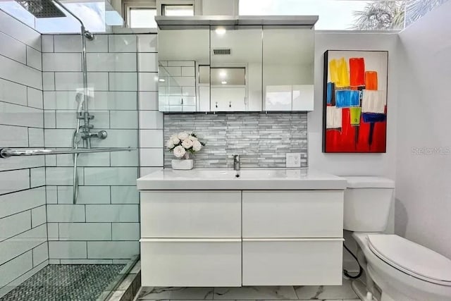 bathroom featuring toilet, tiled shower, visible vents, backsplash, and marble finish floor