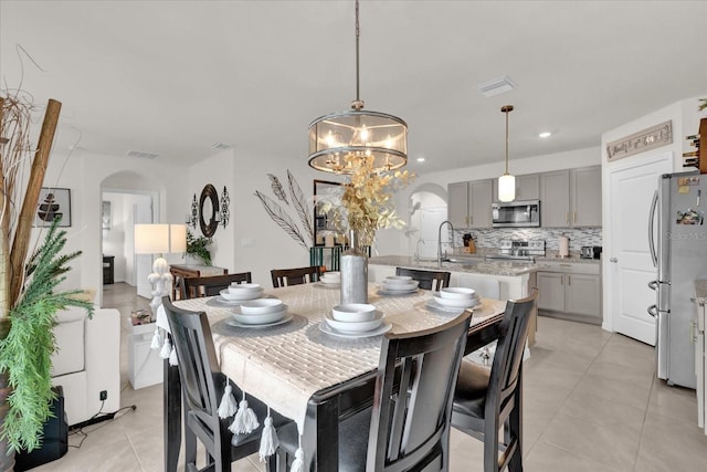 dining area featuring visible vents, arched walkways, a chandelier, and light tile patterned floors