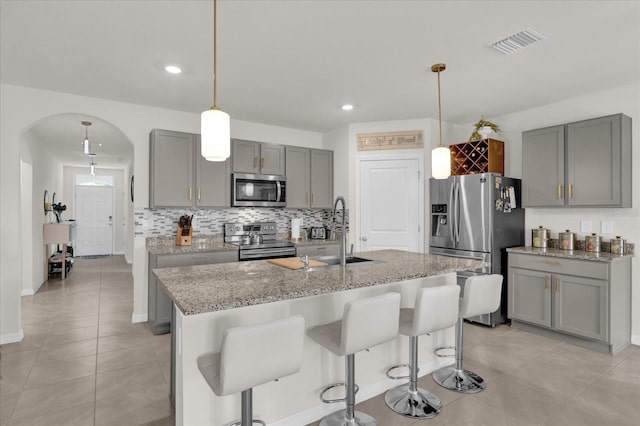 kitchen with arched walkways, a sink, visible vents, gray cabinets, and appliances with stainless steel finishes