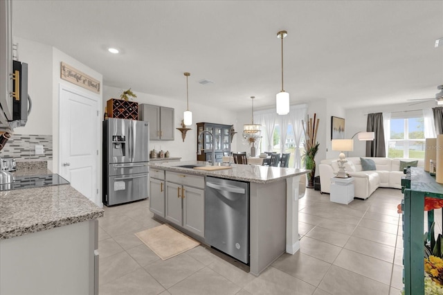 kitchen with a sink, light tile patterned flooring, open floor plan, decorative backsplash, and appliances with stainless steel finishes