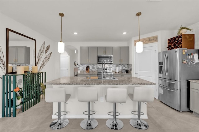 kitchen featuring gray cabinetry, light stone counters, and appliances with stainless steel finishes