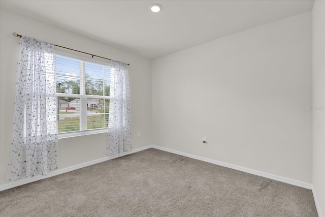 spare room with baseboards and carpet floors