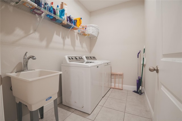 clothes washing area featuring washer and clothes dryer, light tile patterned floors, laundry area, and a sink