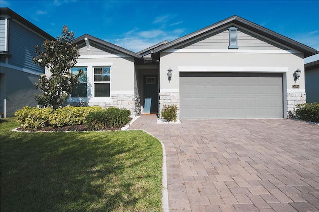 ranch-style home with a garage, a front yard, decorative driveway, and stone siding