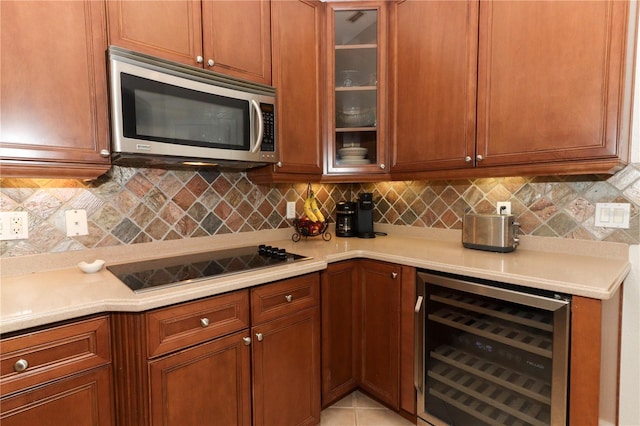 kitchen with stainless steel microwave, wine cooler, black electric stovetop, and light countertops