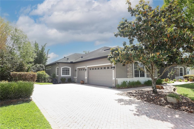 view of front facade featuring stone siding, stucco siding, decorative driveway, and an attached garage