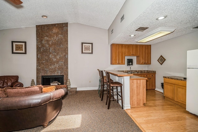 150 Waterfall Way Unit 102, Altamonte Springs, FL 32714 - kitchen featuring a textured ceiling, freestanding refrigerator, a kitchen bar, vaulted ceiling, and a peninsula