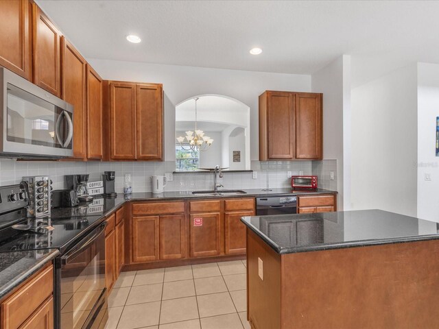 411 Cabello Dr, Davenport, FL 33837 - kitchen featuring backsplash, arched walkways, black range with electric stovetop, a sink, and stainless steel microwave