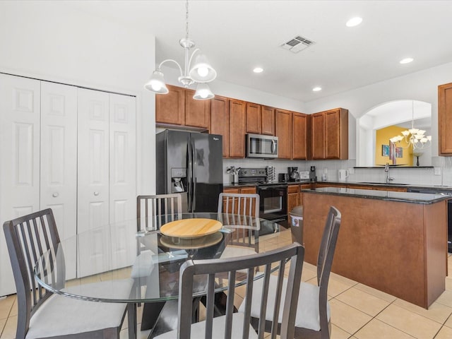 411 Cabello Dr, Davenport, FL 33837 - kitchen with light tile patterned flooring, dark countertops, a chandelier, a sink, and black appliances
