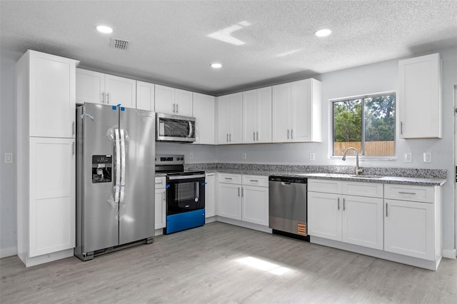 2763 E Waco Dr, Deltona, FL 32738 - kitchen with appliances with stainless steel finishes, a sink, light wood-style flooring, a textured ceiling, and white cabinets