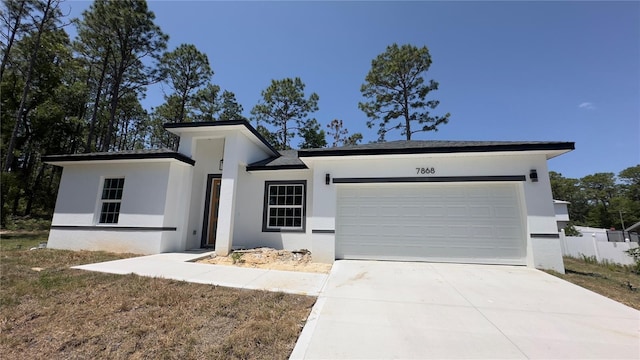 view of front of house with stucco siding, concrete driveway, and an attached garage