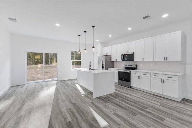 kitchen with stainless steel appliances, light wood-style floors, a sink, white cabinetry, and visible vents