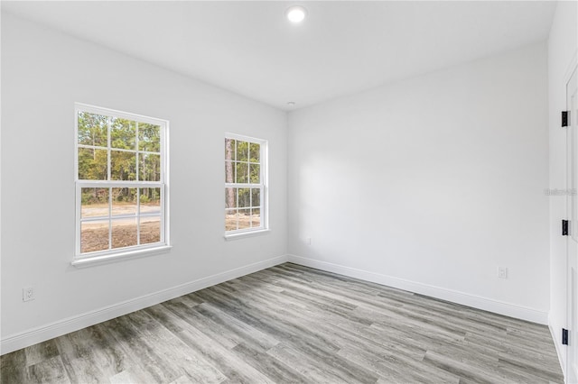 empty room featuring wood finished floors, recessed lighting, and baseboards