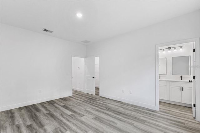unfurnished bedroom with a sink, visible vents, and light wood-style floors