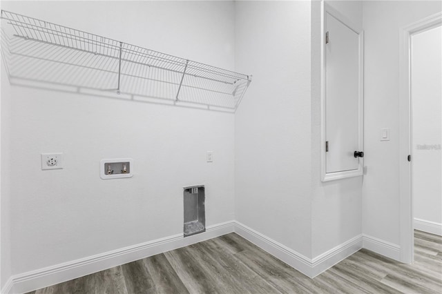 washroom with electric dryer hookup, wood finished floors, laundry area, and baseboards