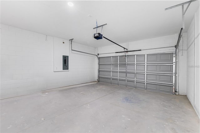 garage with a garage door opener, concrete block wall, and electric panel