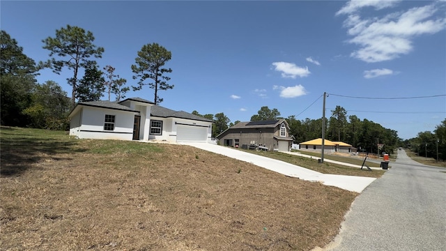 view of front facade featuring a front lawn, driveway, a garage, and stucco siding