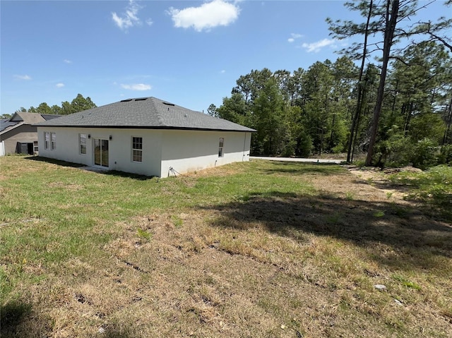 rear view of property featuring stucco siding and a yard